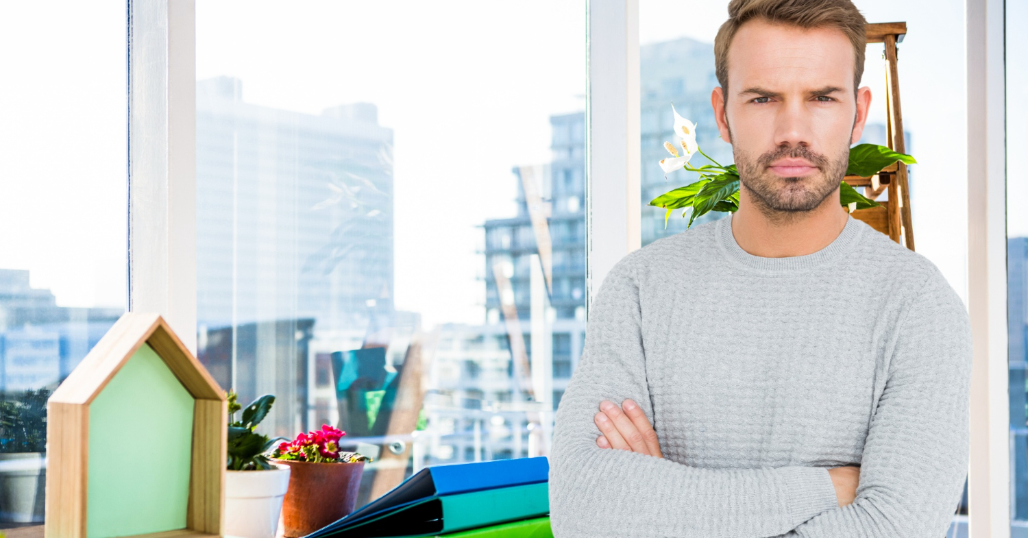 Un homme au regard sérieux À ses côtés, une petite maison en bois et des dossiers de travail