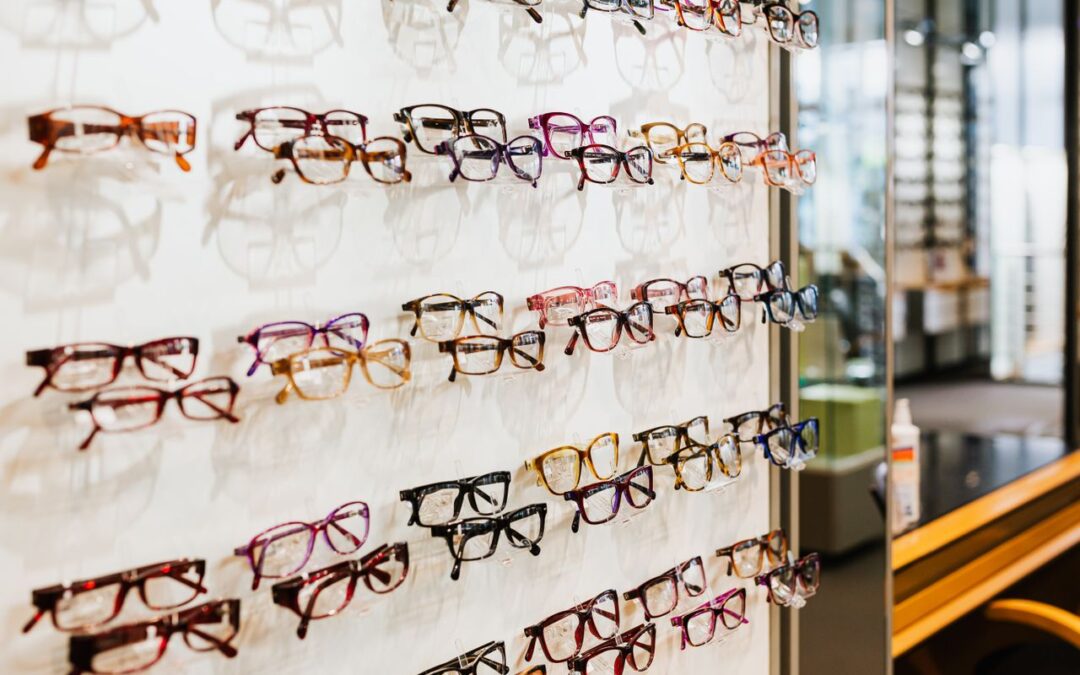 un grand présentoir mural d'opticien exposant de nombreuses montures de lunettes de vue variées, rangées sur plusieurs rangées