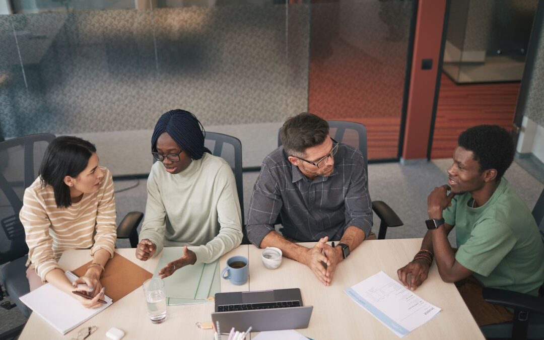 Un groupe de collègues discutant ensemble autour d'une table de réunion dans un bureau moderne