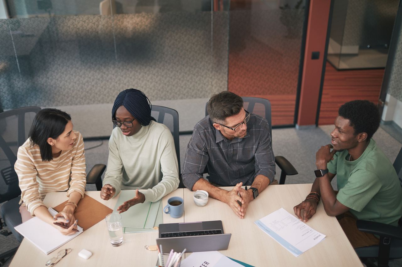 Un groupe de collègues discutant ensemble autour d'une table de réunion dans un bureau moderne