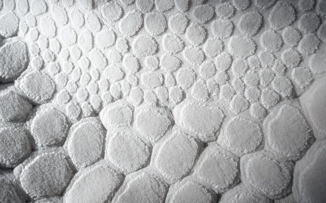 un tapis de bain blanc aux reliefs formant un motif de galets