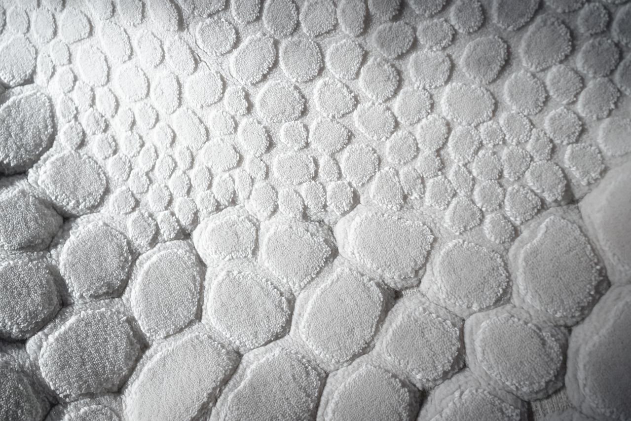 un tapis de bain blanc aux reliefs formant un motif de galets